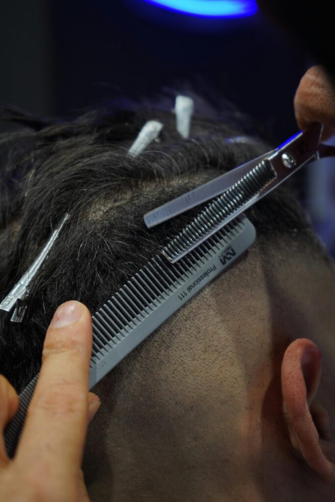 Detailed view of a person getting a haircut using scissors and comb in a barbershop.